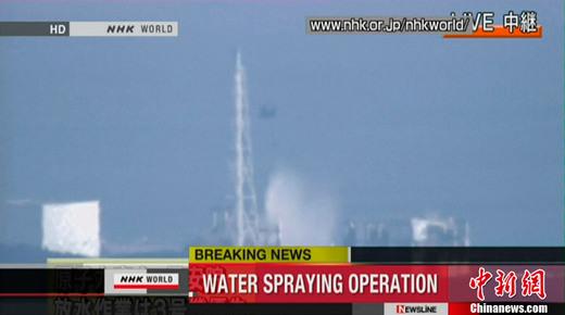 图为直升机向福岛第一核电站三号机组注水过程的电视截图。 图为直升机向福岛第一核电站三号机组注水过程的电视截图。