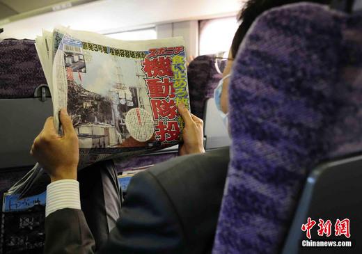 3月17日下午，在一列前往东京的新干线列车上，一名日本人在阅读关于福岛核电站三号机组最新状况的报道。中新社发 侯宇 摄